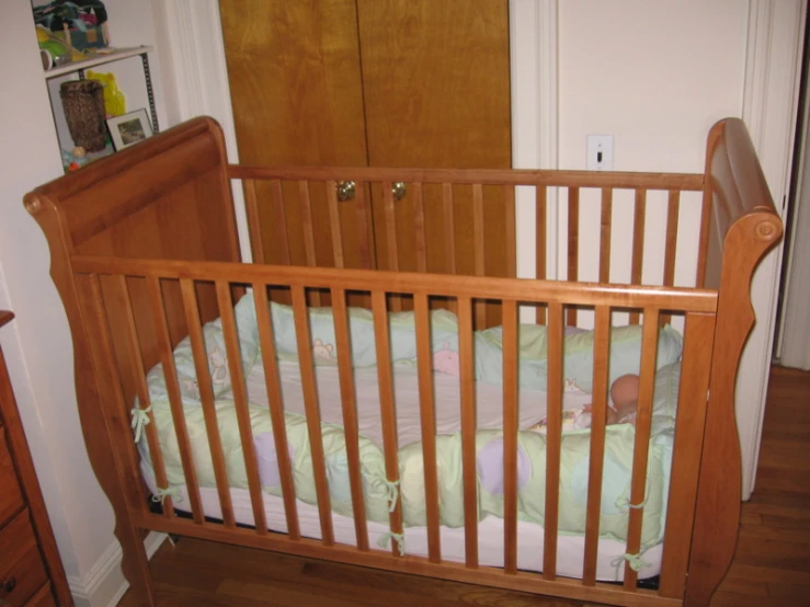 a baby in a wooden crib sleeping on a blanket