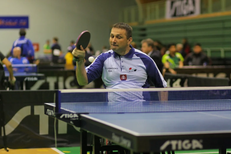 man holding a ping pong paddle while playing on a table tennis