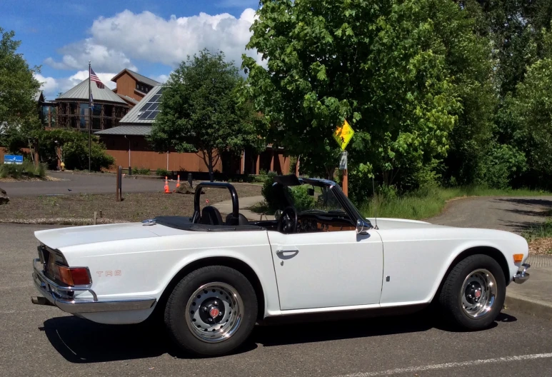 an old convertible is parked in the middle of a road