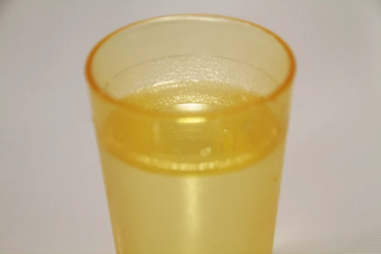 a glass of orange juice on a white table