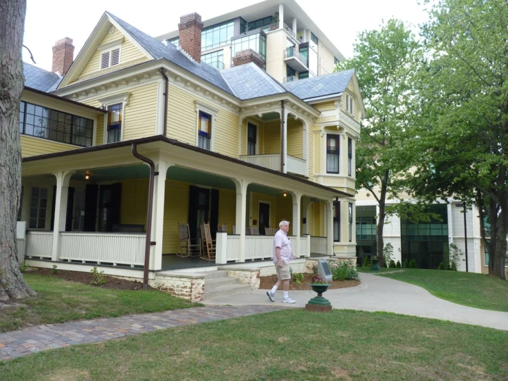 woman walking through front of a two story yellow house