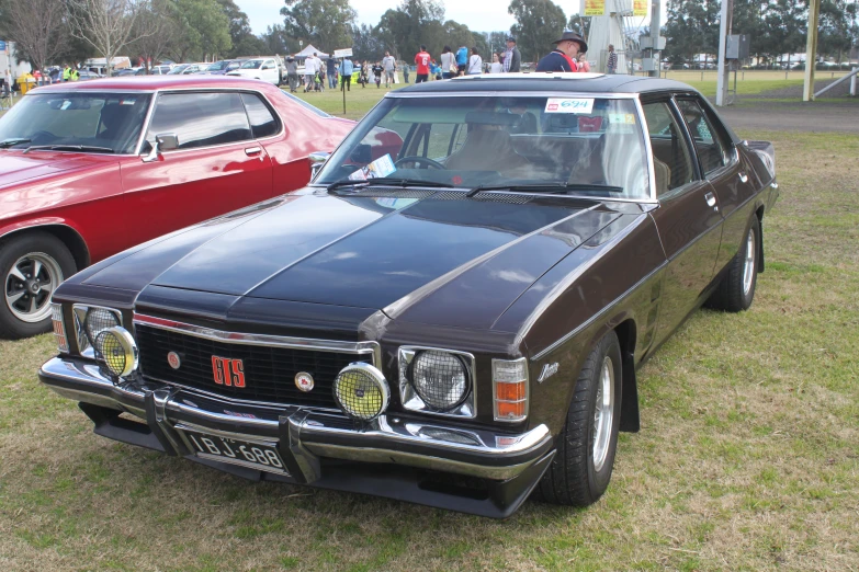 two old station wagon cars on display with people