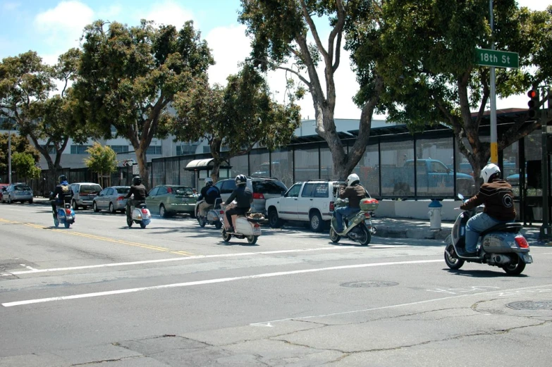 several people riding motor bikes on a city street