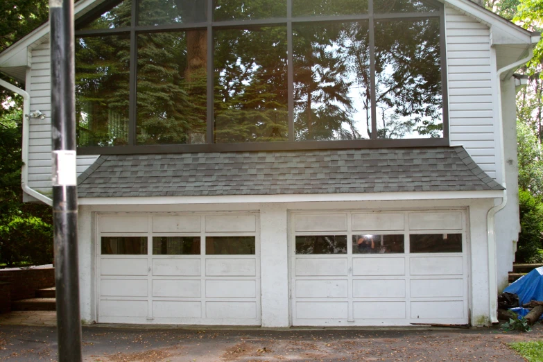 a garage with two windows next to the trees