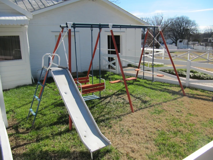 a small child's swing set with a slide in the grass