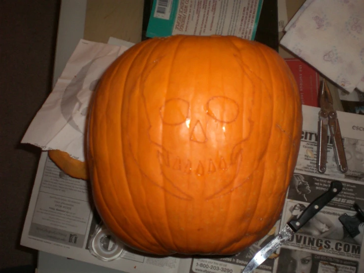 a pumpkin with a face carved on it sitting next to scissors