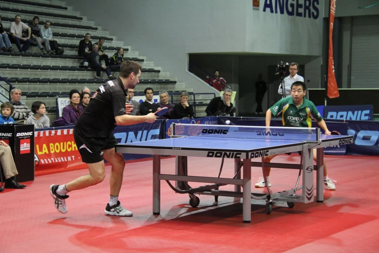 a man is playing ping pong against another person