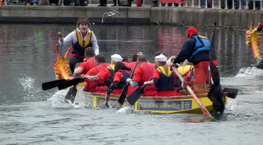 people dressed in red row a small boat