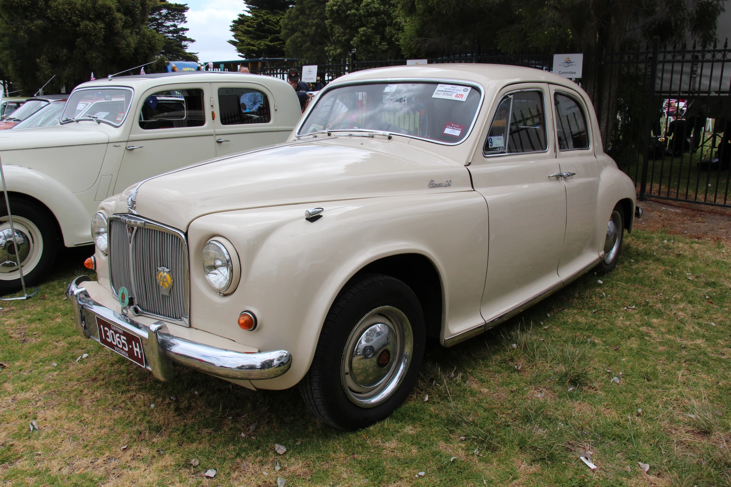 two antique cars parked next to each other on a field