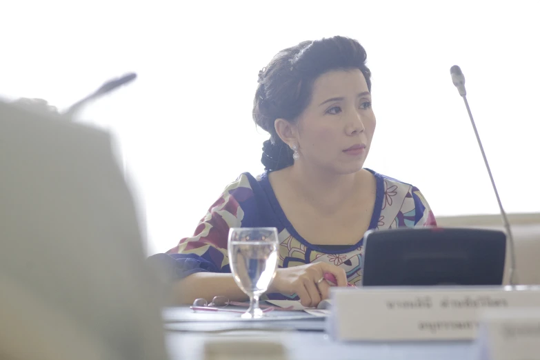 a woman sitting at a table with a microphone