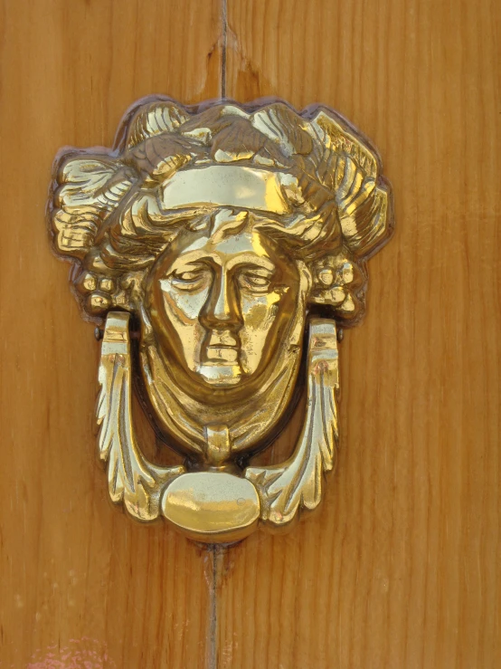 a large, gold, door handle featuring a woman's face