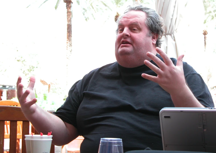 a man in black shirt sitting at table with glass