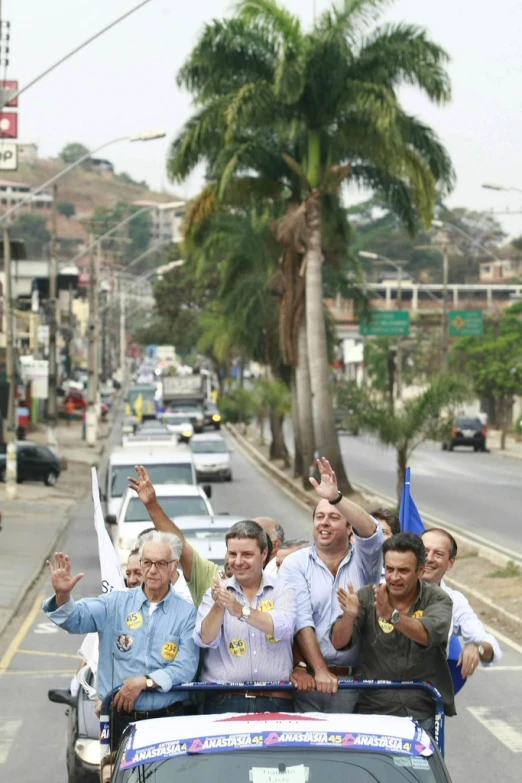 a crowd of people are waving on the back of a vehicle