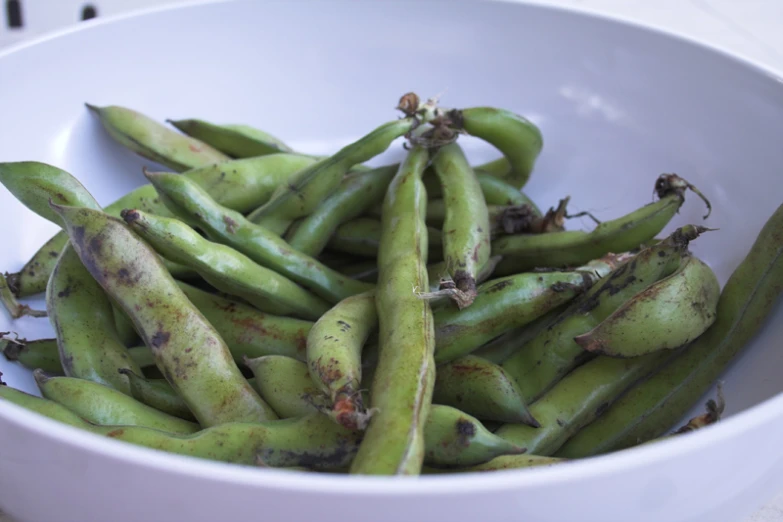 a white bowl filled with green beans on a table