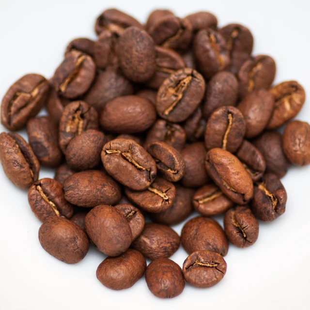 coffee beans are piled up on a white surface