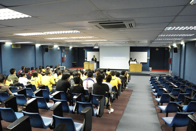 a large conference room full of people sitting at their desks