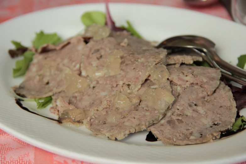 a fork on a white plate holding a meat salad