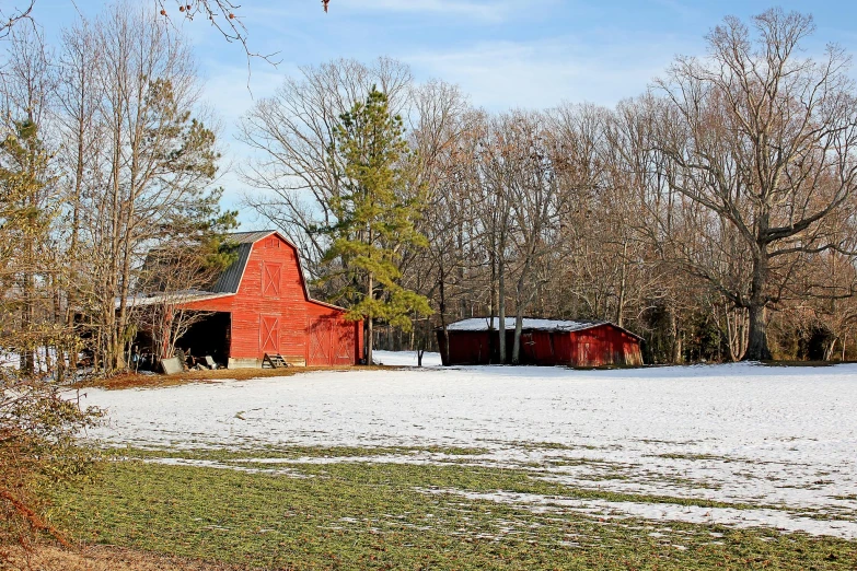 a barn on a snow covered landscape, with a few trees