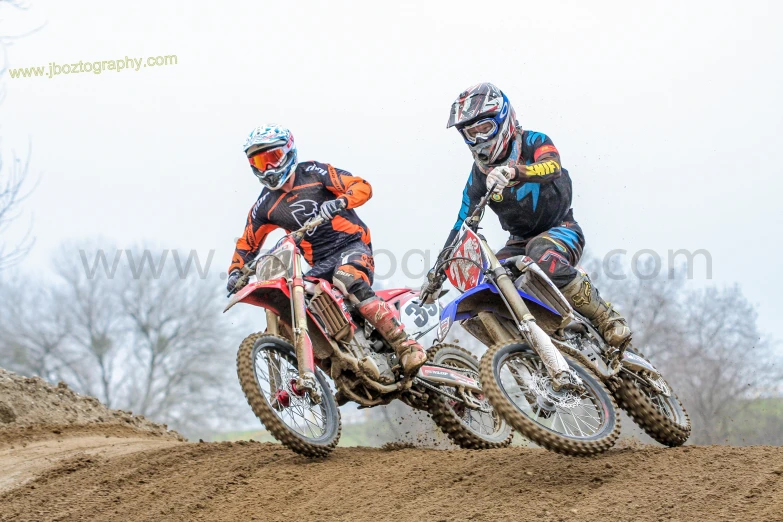 two people riding on dirt bikes in the dirt
