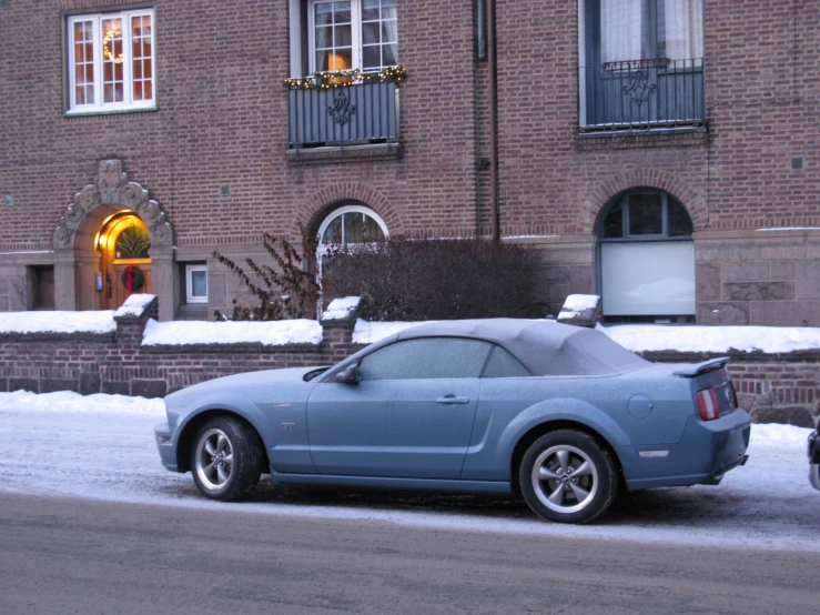 a car parked outside a tall brick building in a winter scene