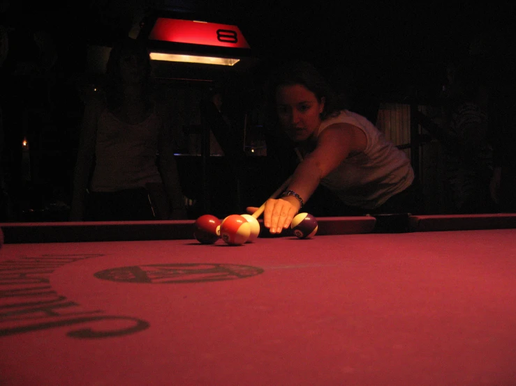 woman playing billiard in darkened arena at night