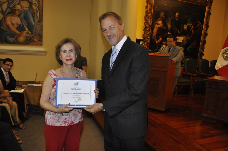 a man is holding up an award plaque next to an older woman