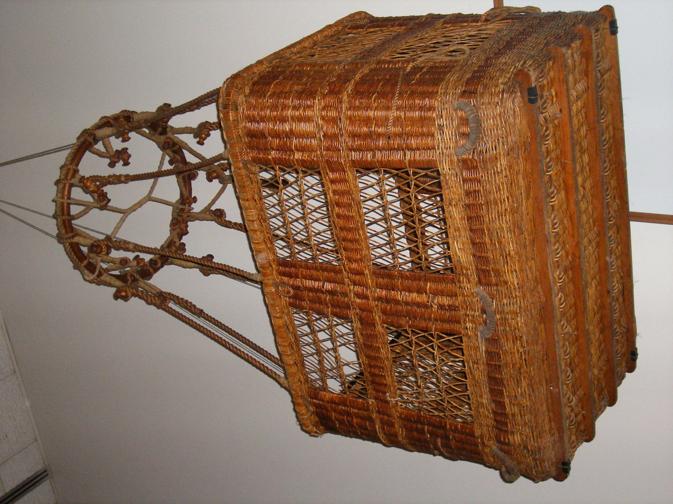 a brown basket with a handle on a white wall