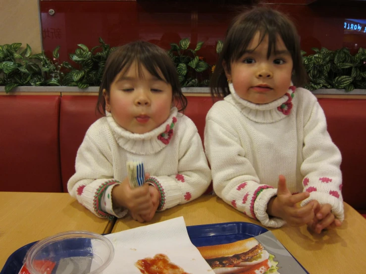 two children sitting at a table in front of pizza