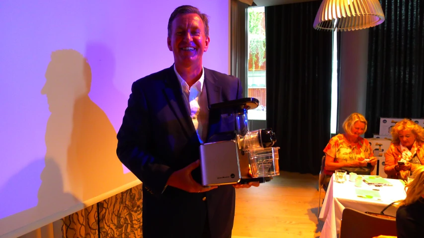 a man holding an award while standing in front of a table