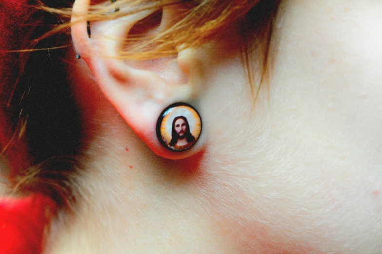a person has been put in a small earring with an image of jesus on it