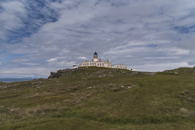 a large white building sits on top of a grassy hill