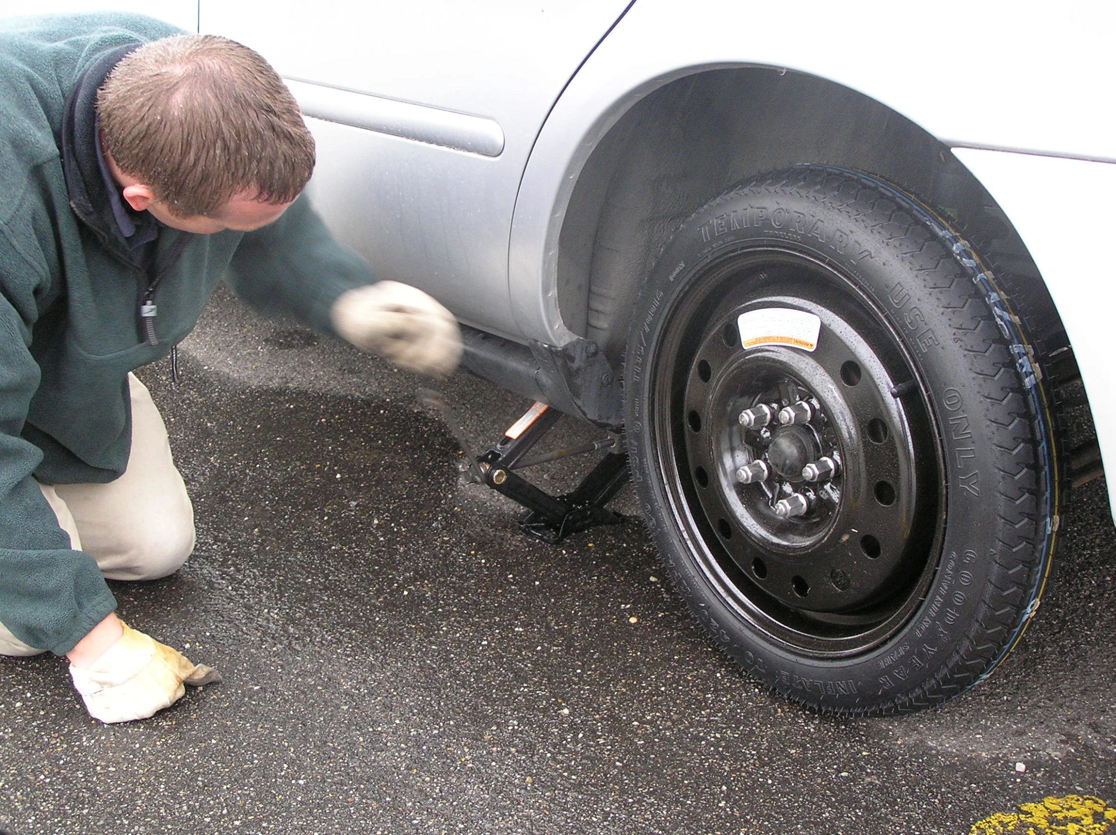 a person fixing the wheel of a white car