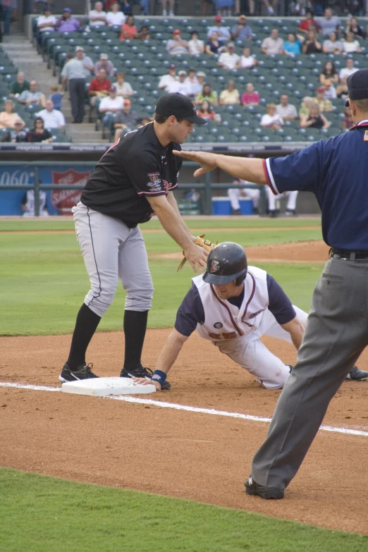 a man has his leg on the base as he is taken down by a umpire