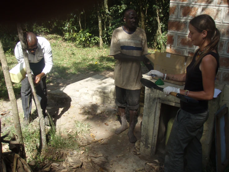 an outdoor area with two people, one working with shovels and another holding a water bucket