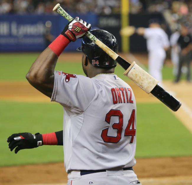 a baseball player holds up a bat in the batter's box