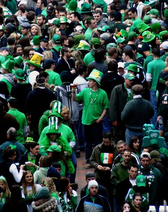 a crowd of people in green shirts and hats