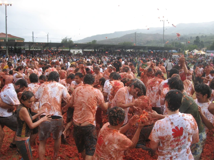 a crowd covered in orange colored powder and water