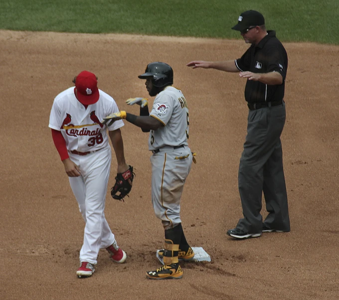 two baseball players talking on the field as referee points to one