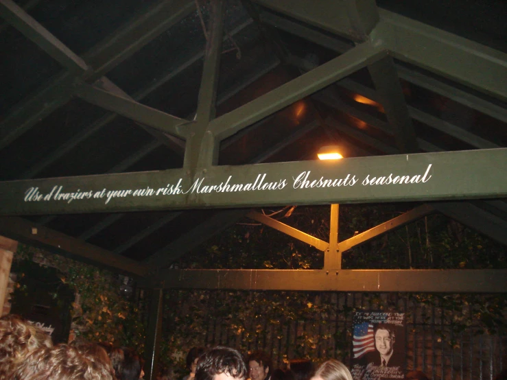 people standing under a green overhead wooden sign