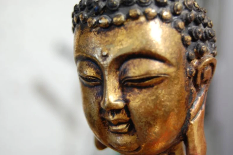 a buddha statue sits alone in front of a white wall