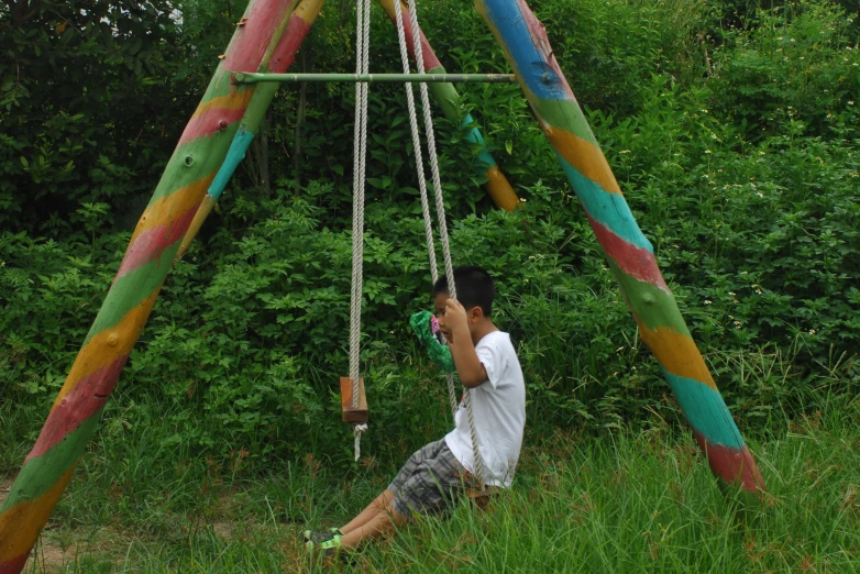 a young man in the grass blowing on an outdoor playground