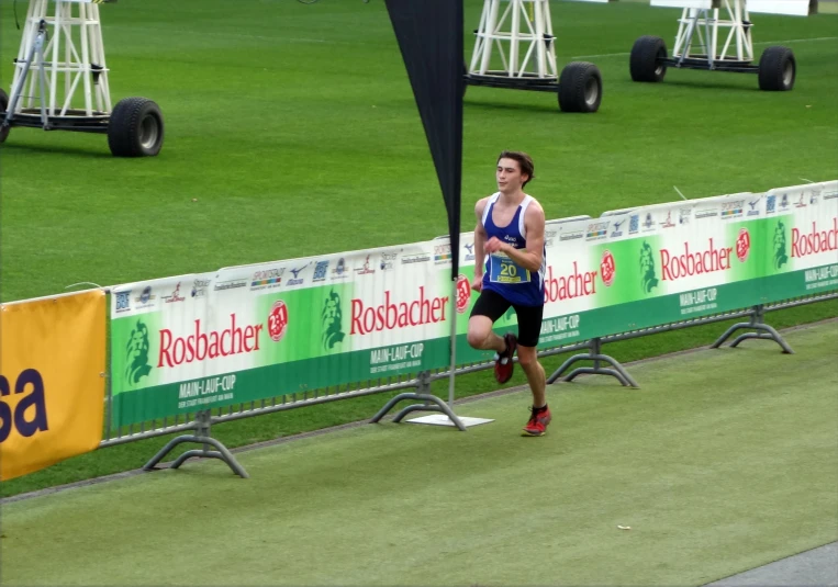 a man is running down the grass with a race marker in the background