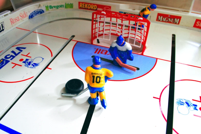 two people play with hockey toys on an ice rink