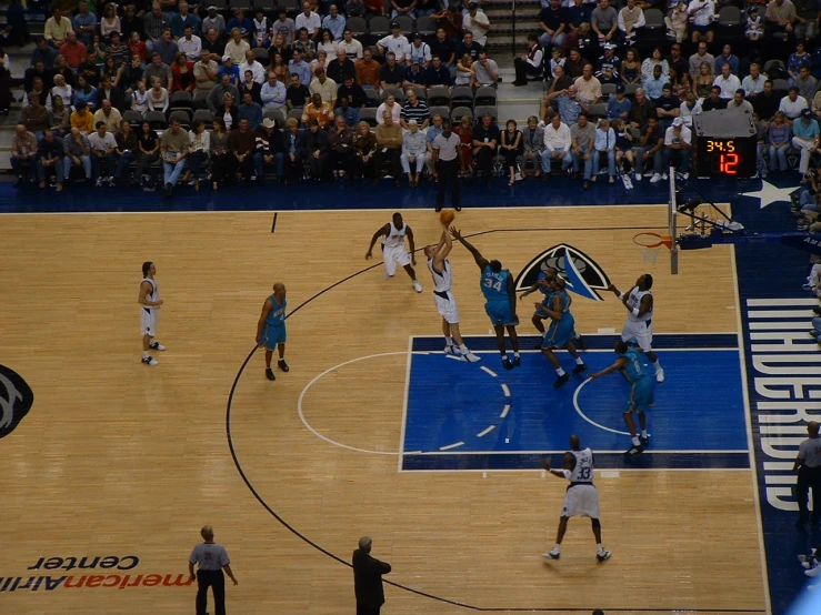 several men play basketball in front of spectators