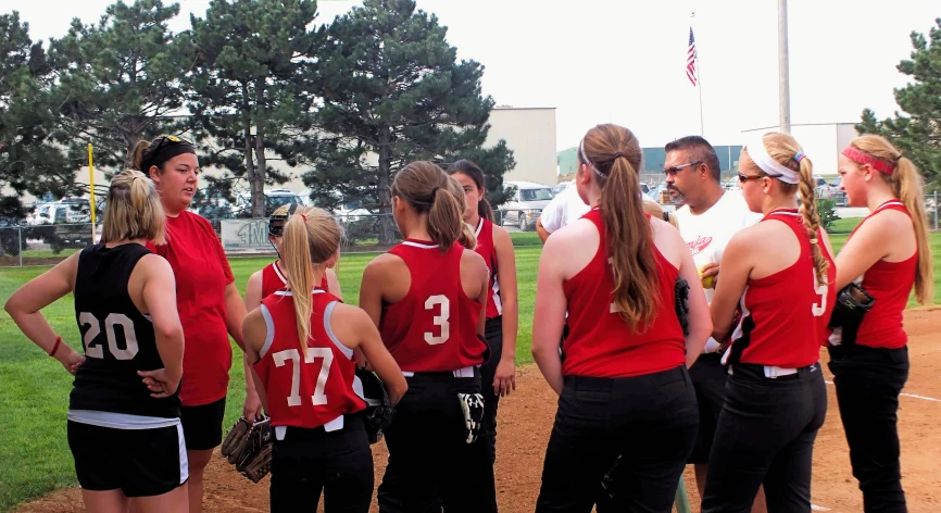 a group of women standing on a baseball field with their backs to each other