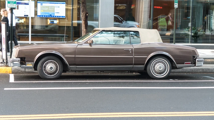 the brown car is parked in front of a building
