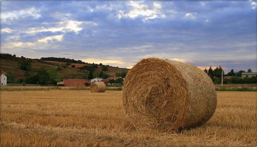 two large bales of hay in a big field