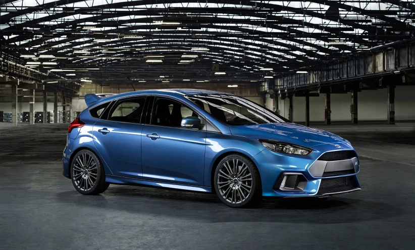 a blue colored car with large circular beams is parked inside a very dark room