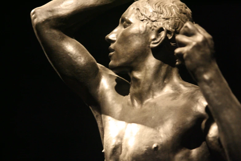 a bronze statue holding a head and looking at the sky