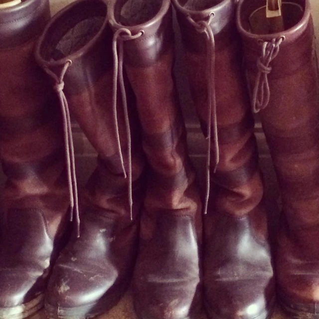 many boots lined up on a shelf near each other